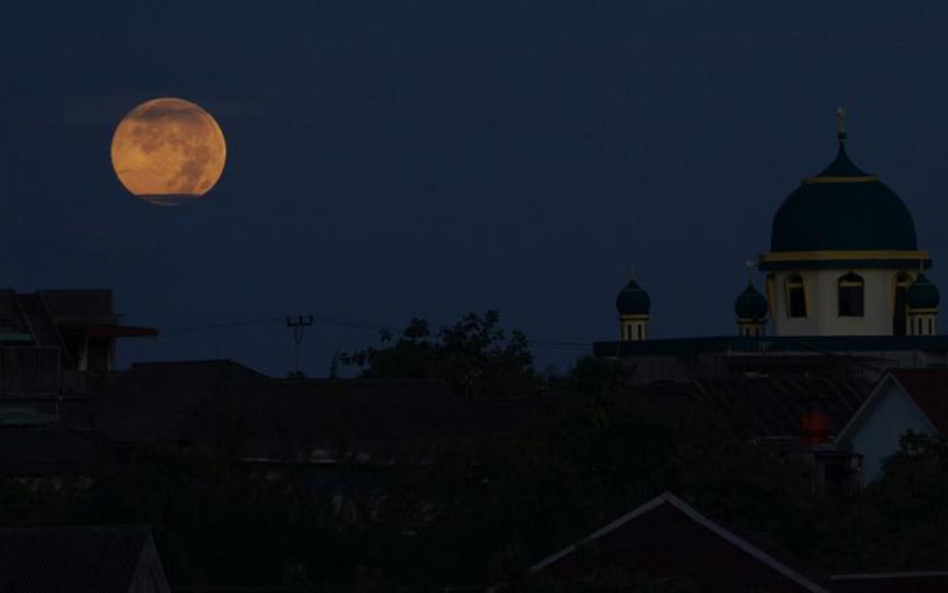 يُنظر للقمر العملاق إلى جانب مسجد من منطقة سكنية في مدينة تانجونج بينانج الإندونيسية