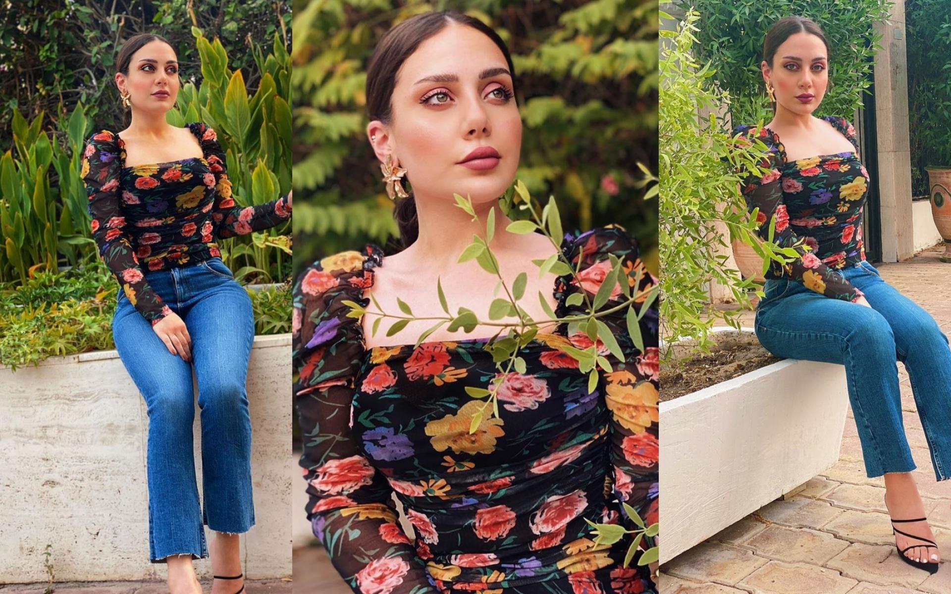 إطلالة نهارية من خلال تنسيق توب بنقشة الورد وبنطلون جينز مع صندل أسود وشعر مربوط