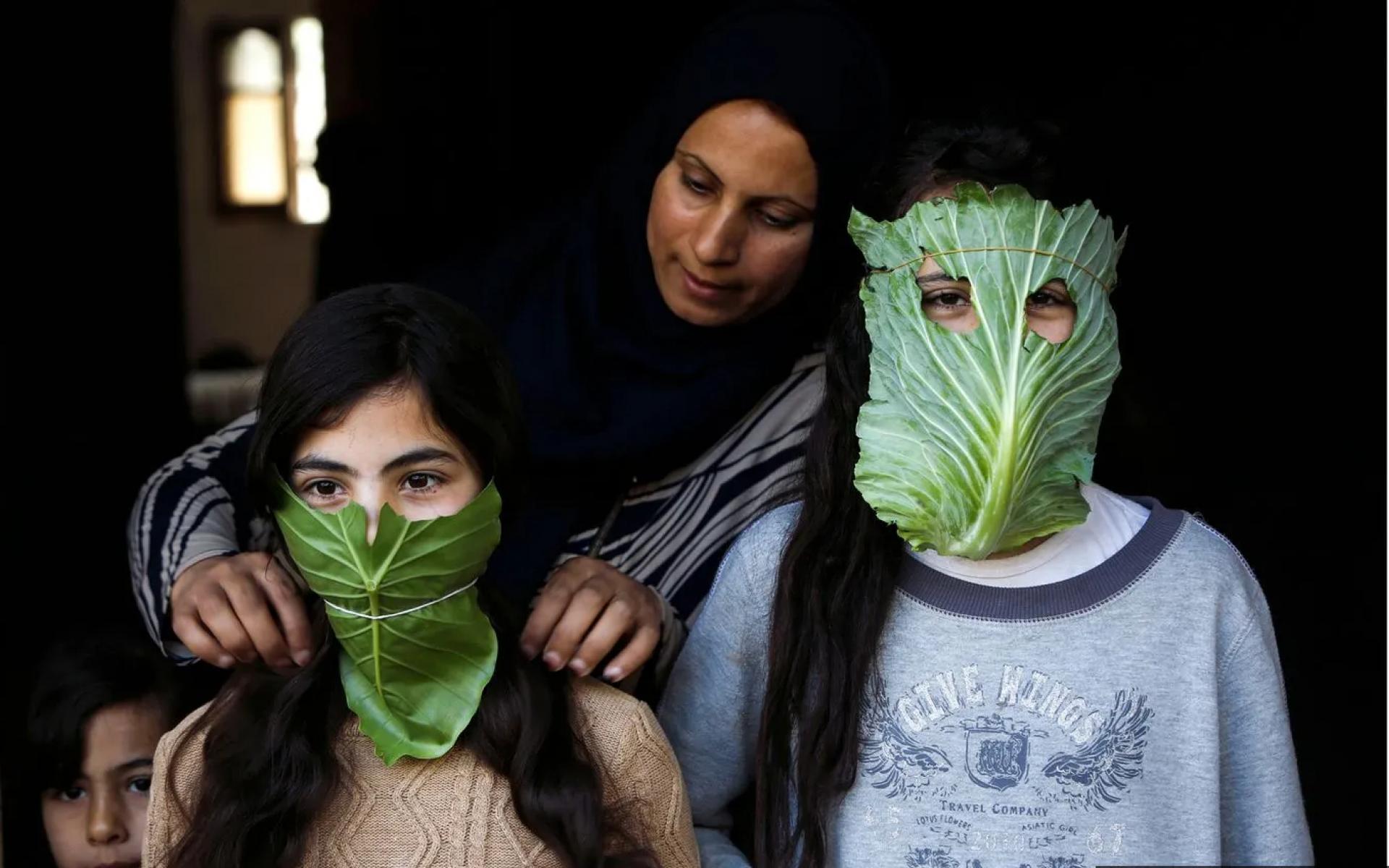 أم فلسطينية ترفه عن أطفالها بأقنعة مصنوعة من الملفوف أثناء الطهي، نيسان 2020